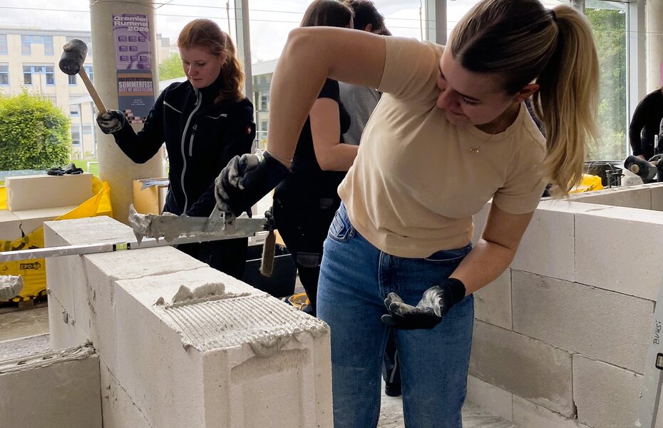 Architekturstudierende tauschen sich beim Tag des Mauerwerks in Dortmund mit Fachleuten über praktische Aspekte des Mauerwerksbaus aus.