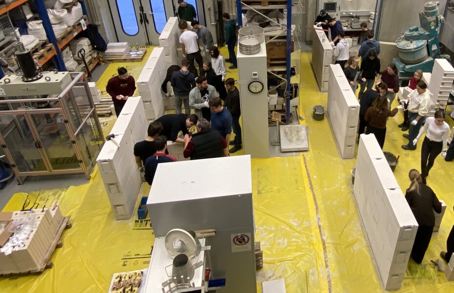 Bauingenieur-Studierende arbeiten in Gruppen an Mauern aus großformatigen Mauersteinen.